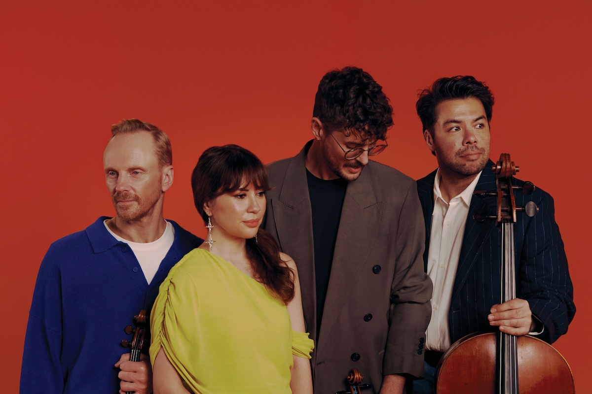 Australian String Quartet musicians posing together with their string instruments against a bold red background.